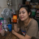 ผู้ใช้งานถือมือถือแสดง Mega Win 56,700 ภาพประกอบรีวิวเล่นสล็อต TUNDER24HR